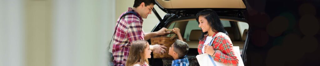 Parents and two children packing picnic supplies into the back of a car