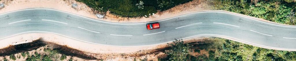 Overhead shot of red car driving down a winding road